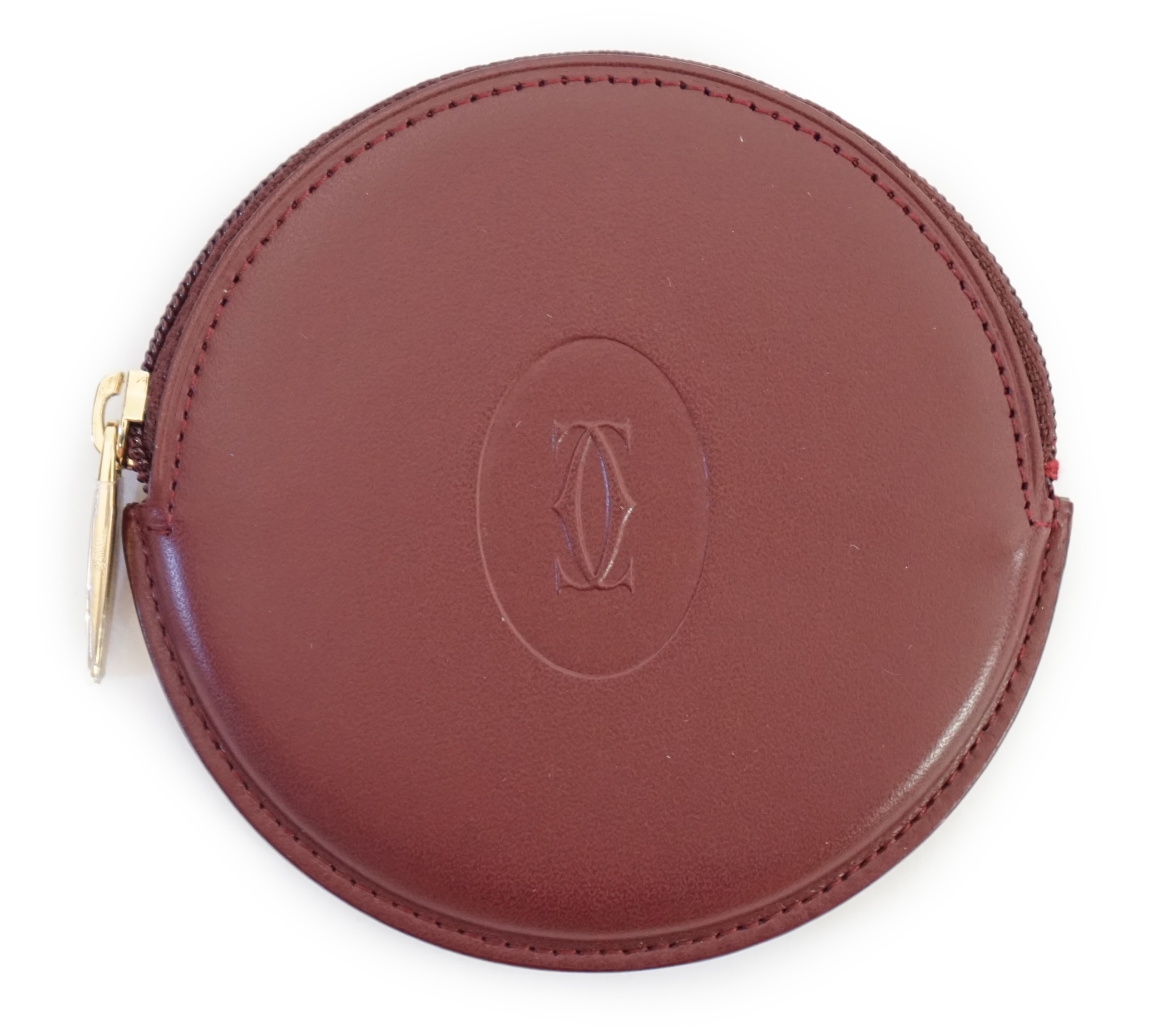 A Cartier maroon leather circular purse with box.